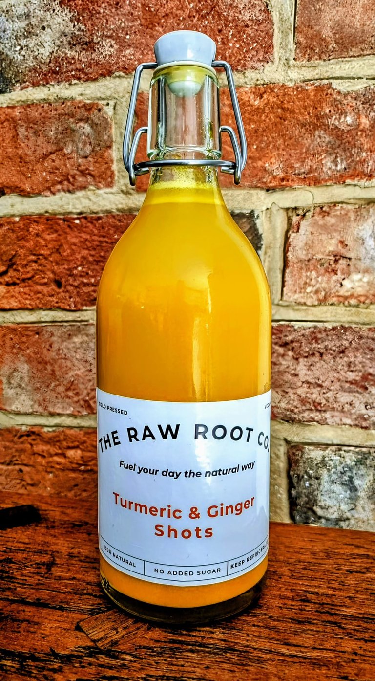 Turmeric and Ginger swing top shot bottle from The Raw Root Co. The Turmeric and Ginger juice is a vibrant orange colour.