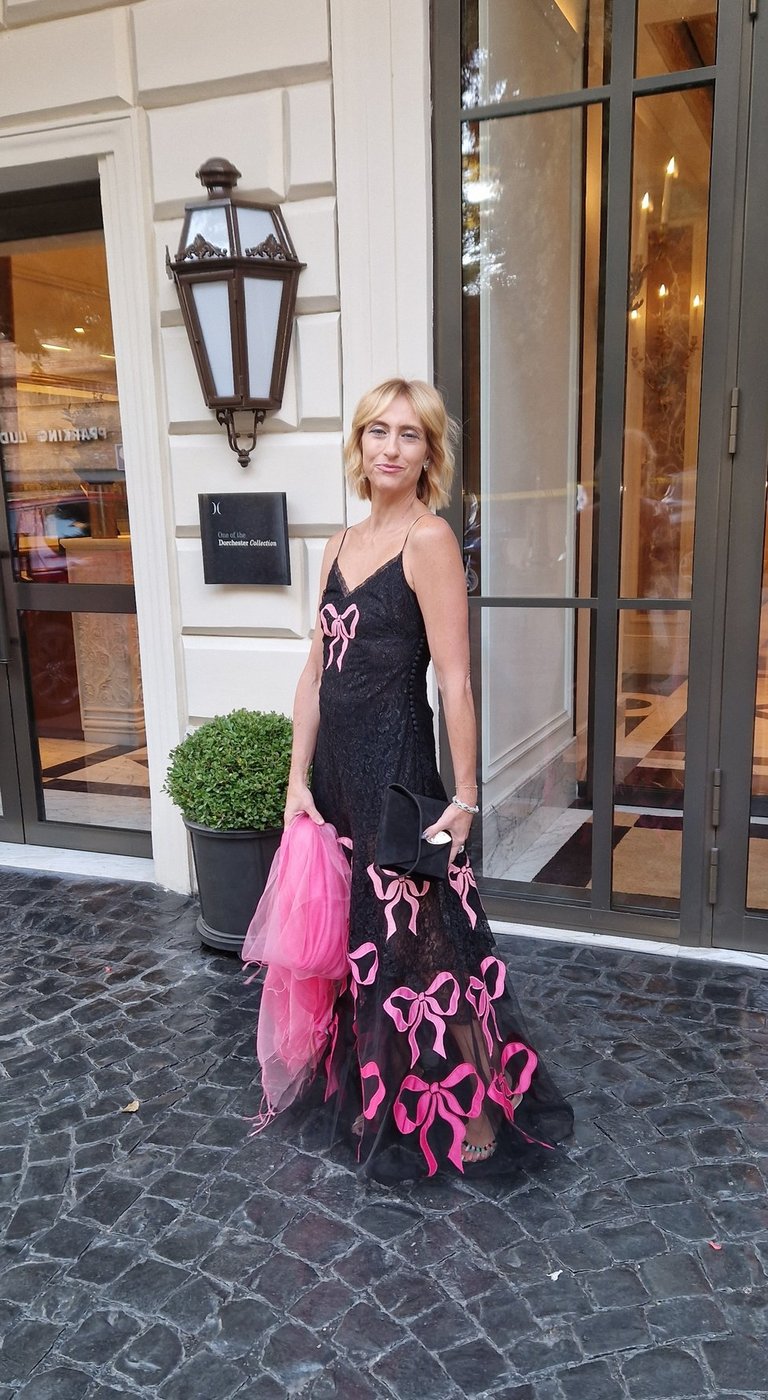 Mary Tornariti outside Hotel Eden Rome in a black gown with pink bows.