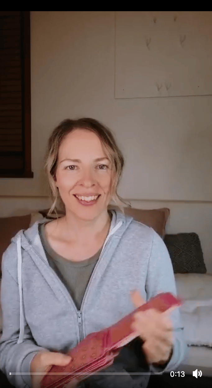 Natalie holding the Five of Pentacles reversed in a live tarot reading.
