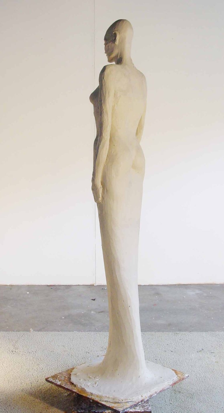 a clay model of a woman standing in a dress