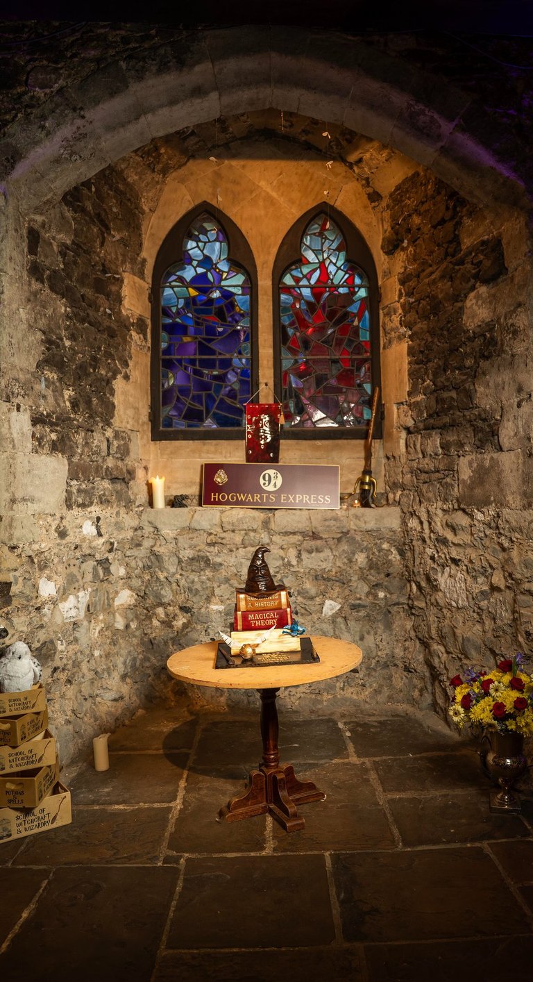 Harry Potter–themed birthday cake table by stone wall and stained glass, Fred Art Studio.