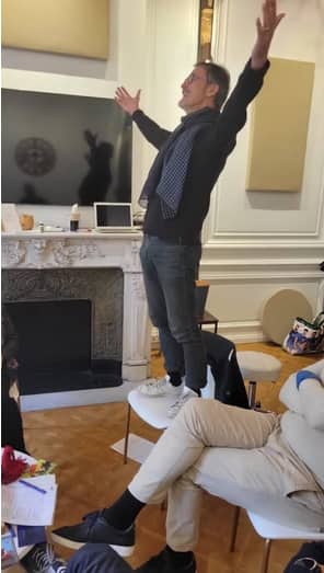 Un homme debout sur une chaise en pleine exaltation.