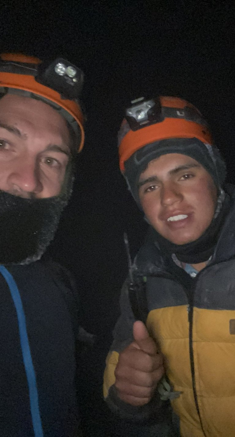 Grupo de montañistas sonriendo y abrazados en el punto de cumbre del volcán.