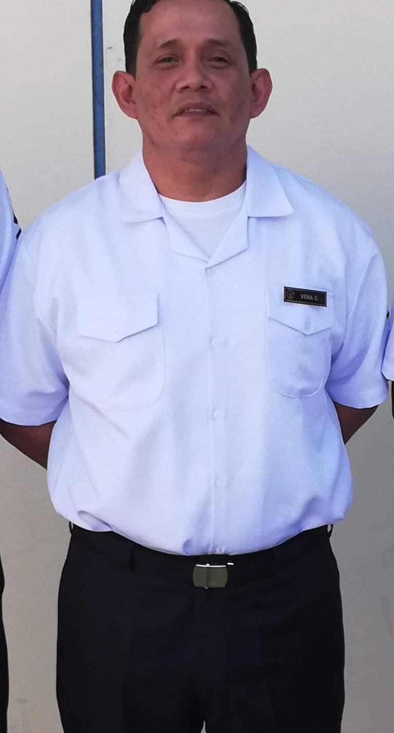 Professional man wearing a white short-sleeve uniform shirt with a name tag and black trousers.