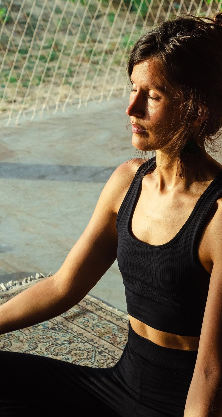 Woman meditating in yoga shala with eyes closed in afternoon sunlight, meditation