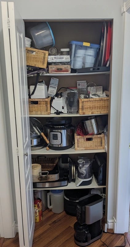 Old kitchenware closet with bowed melamine shelving