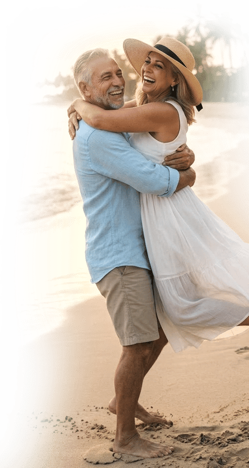 Happy senior couple hugging and laughing on a tropical beach during a romantic sunset vacation.