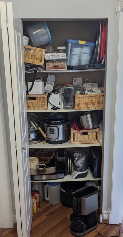 Old kitchenware closet with bowed melamine shelving