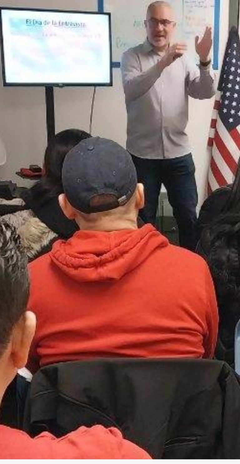 a man in a red jacket is giving a presentation