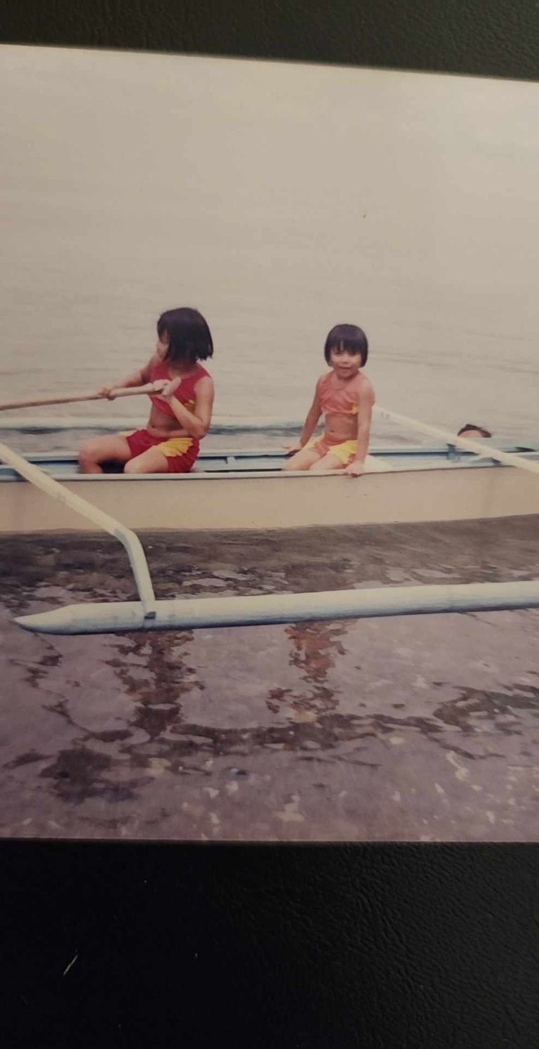 My sister and I on a tropical boat in the water as children.