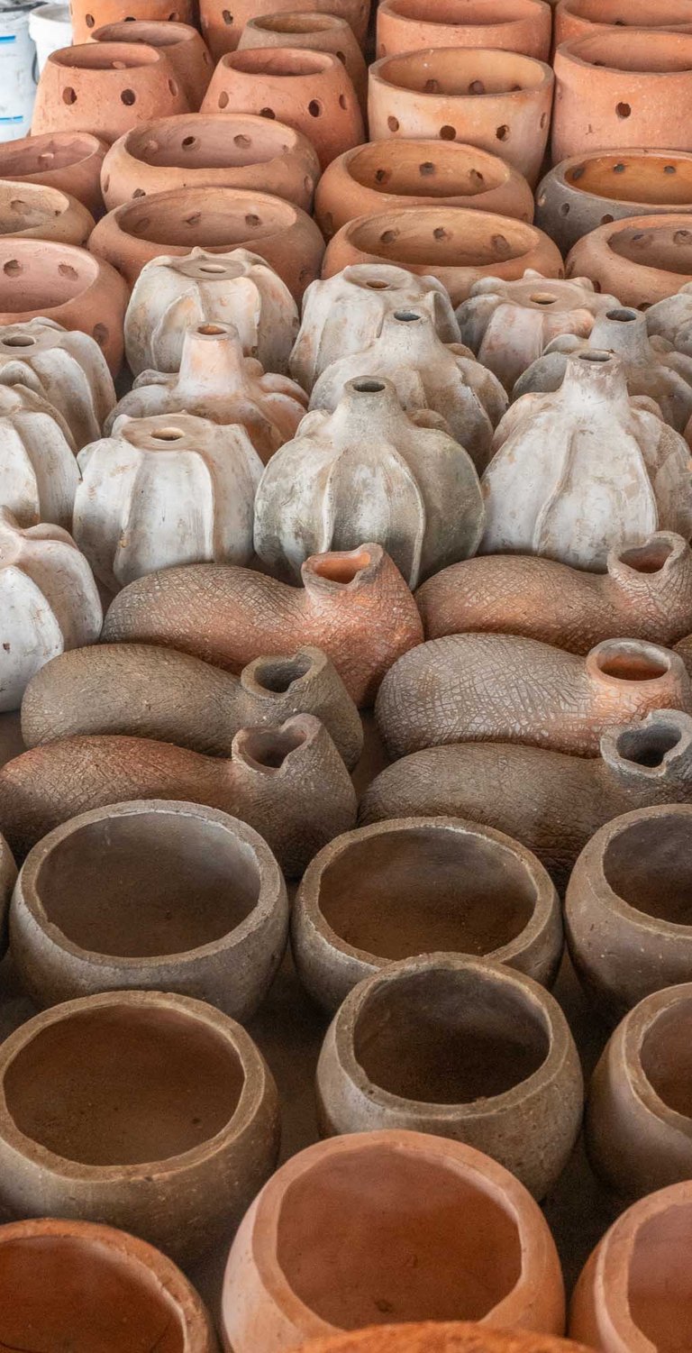 Long row of clay products from bird nests to pots of various sizes and shapes