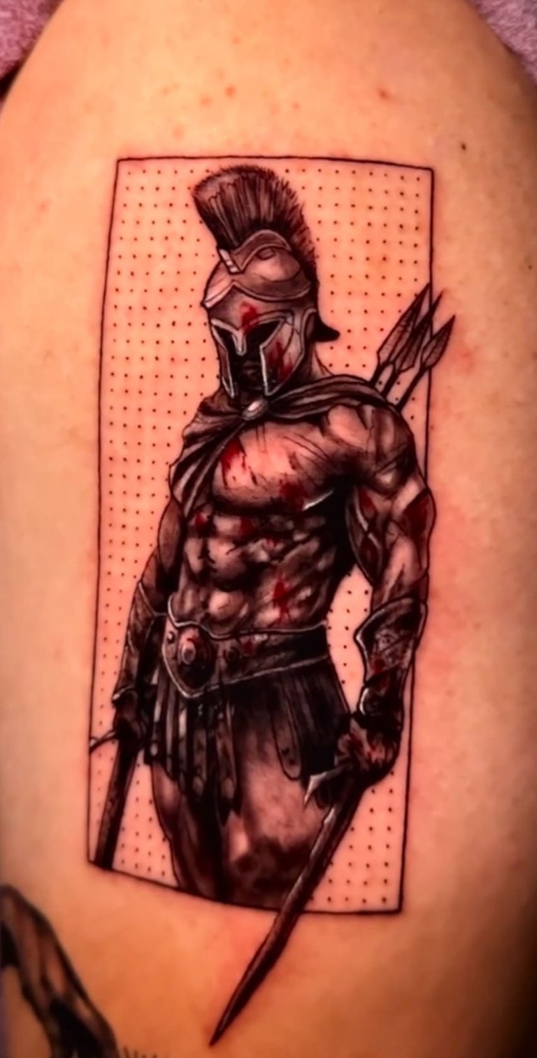 Detailed Spartan warrior tattoo with helmet, spear, and blood splatter on skin.