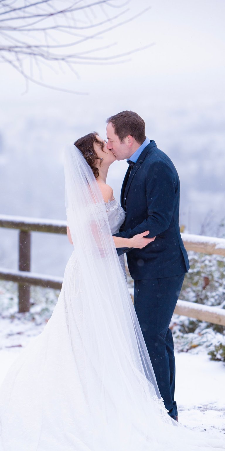 a bride and groom kissing in the snow