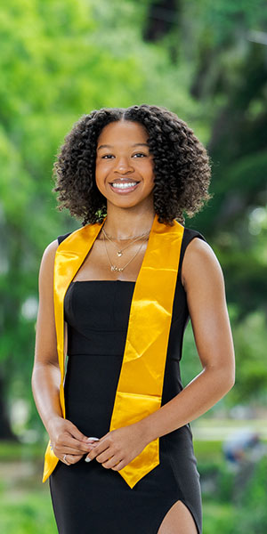 a woman in a black dress and yellow sasher belt