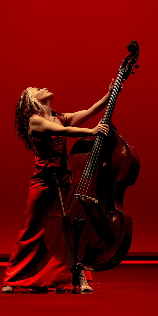 a woman in a red dress playing a doublebass