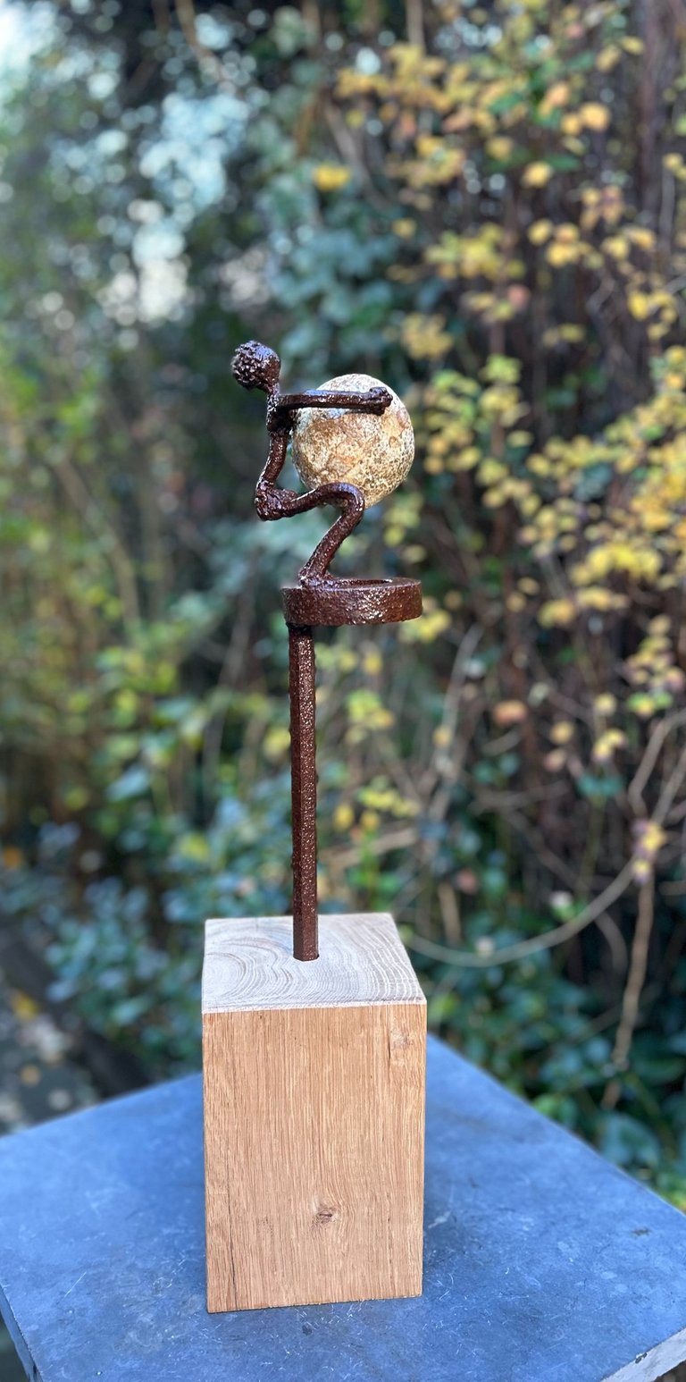 Iron sculpture with stone on wooden pedestal