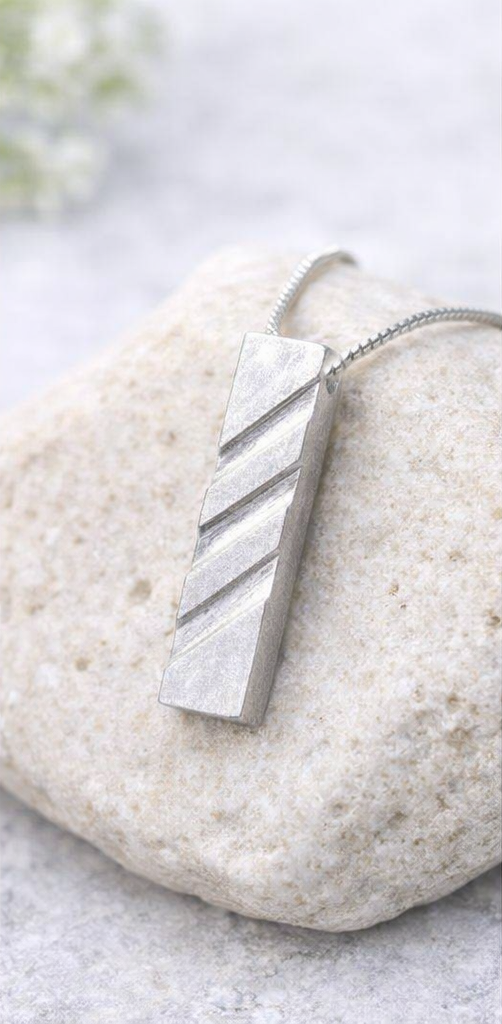 Handcrafted modern 999 fine silver pendant necklace displayed on a white marble surface.