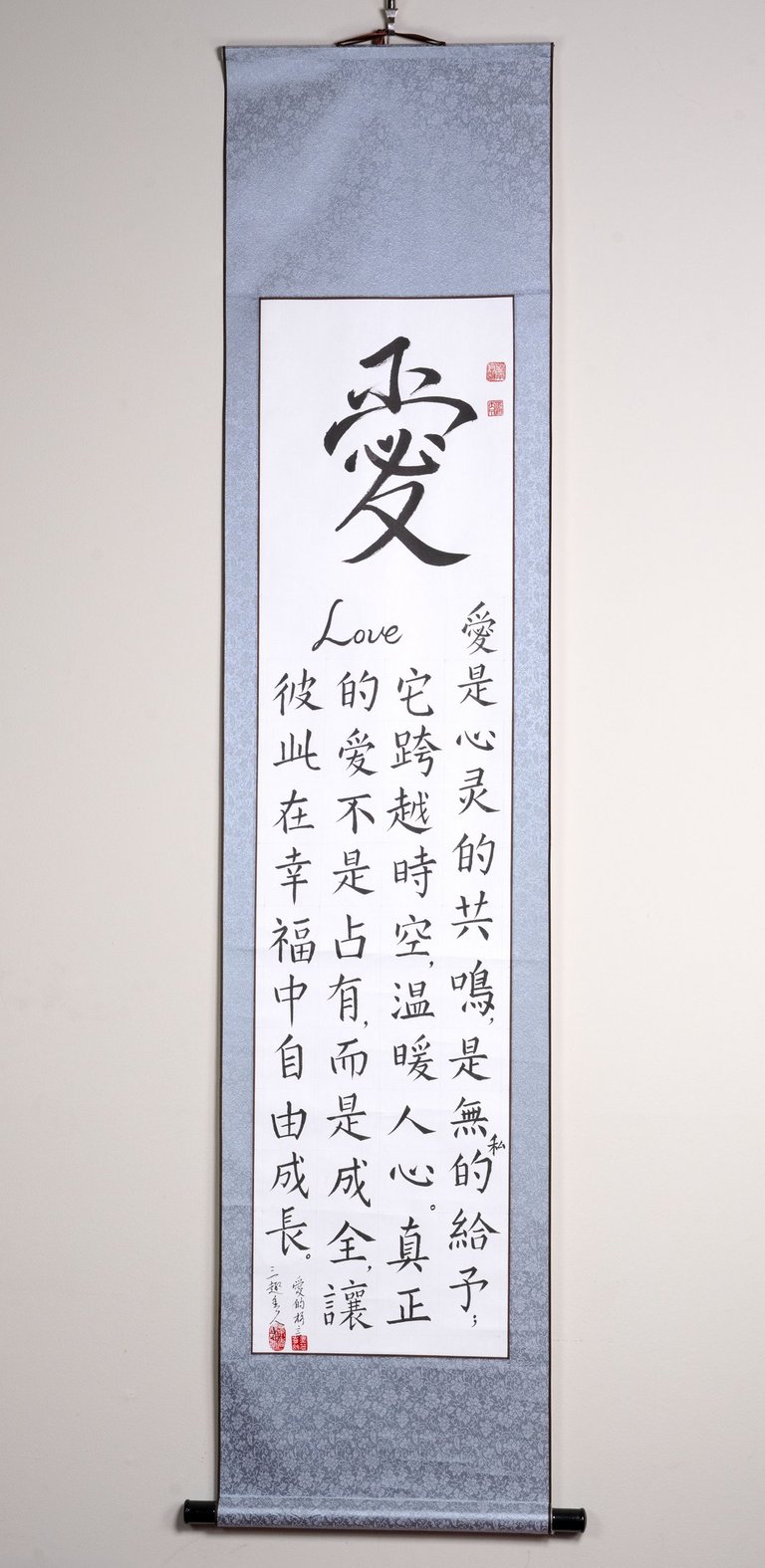 Vertical wall scroll featuring elegant Chinese calligraphy and a poem about the meaning of love.