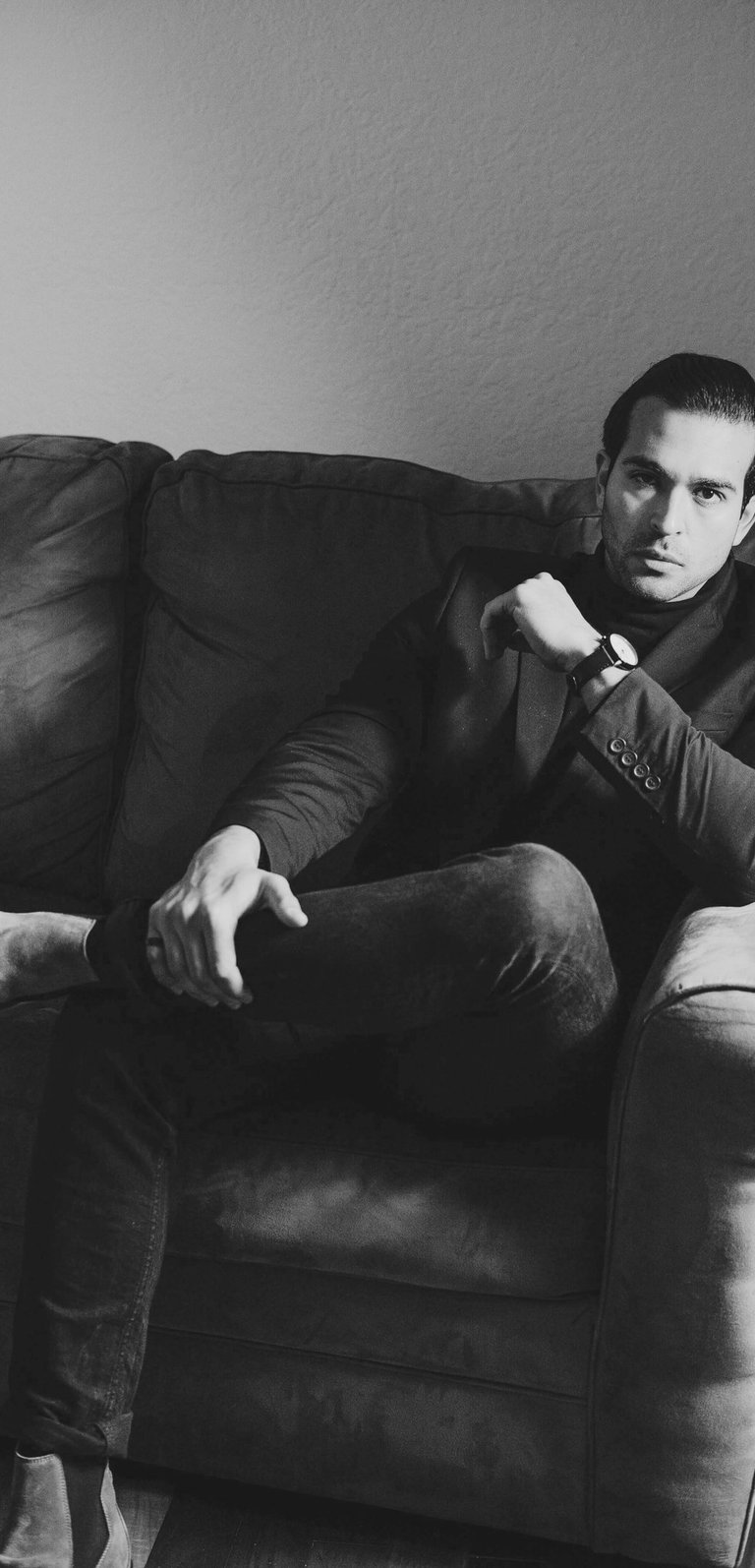 Stylish man seated on a sofa, illustrating the attractive quality of confidence in dating culture