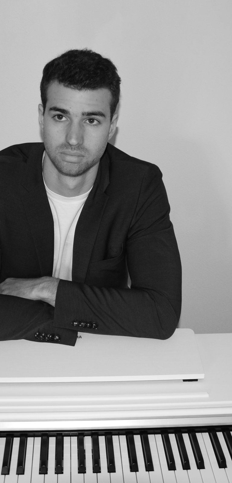 a man in a suit and tie sitting at a piano
