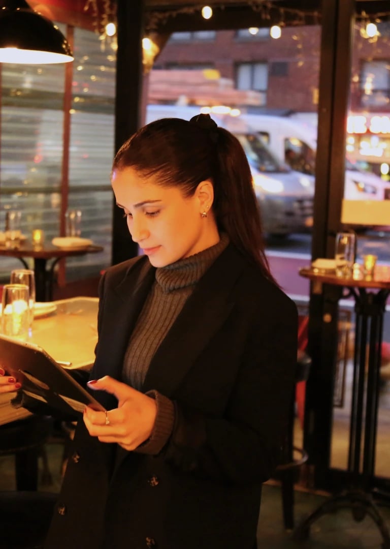 Young woman looking at a tablet, with a restaurant interior visible in the background