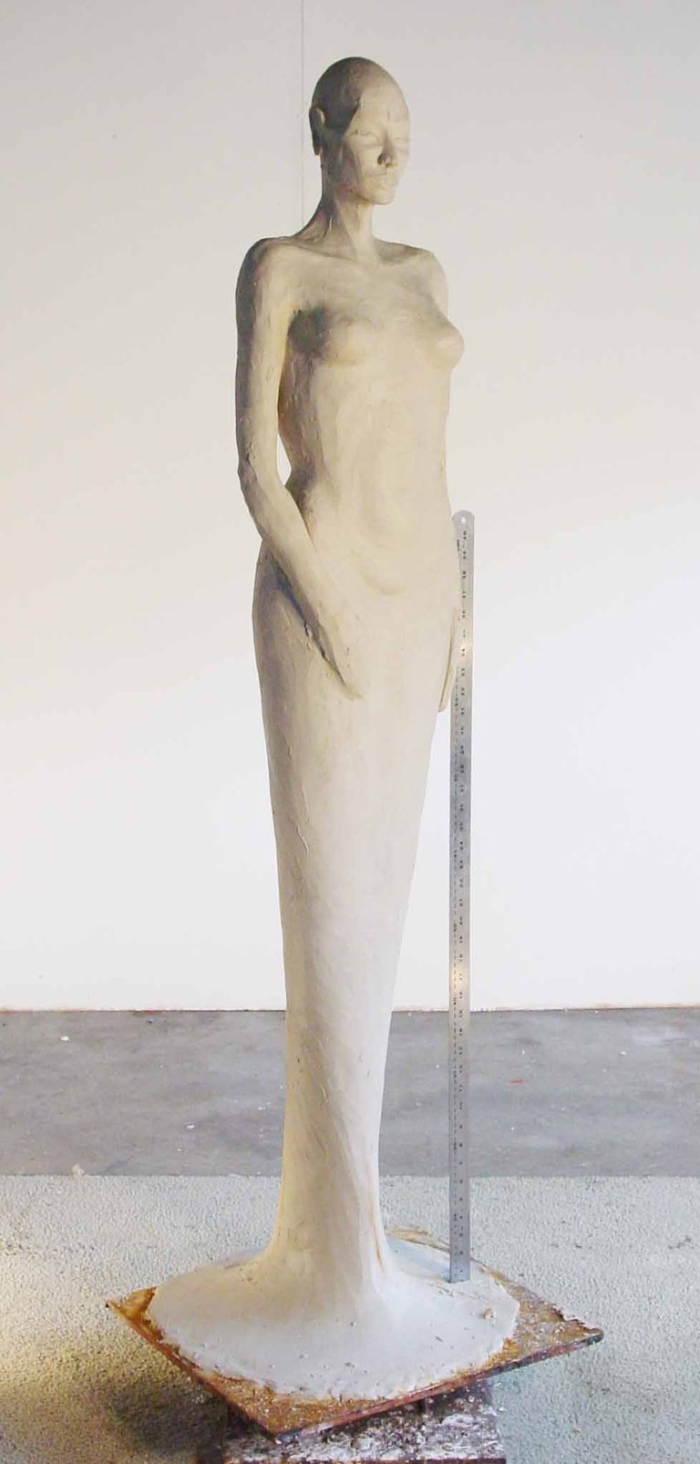 a clay model of a woman standing in a dress