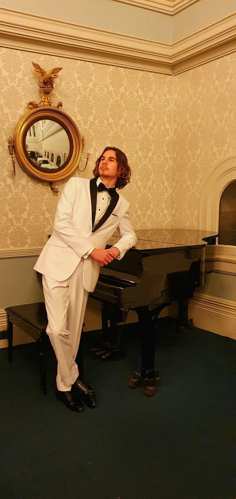 a man in a white suit and a piano