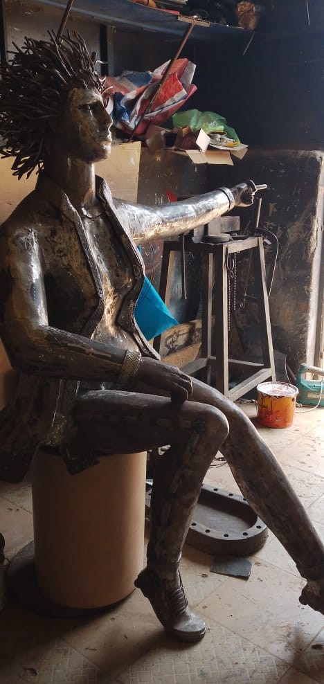 Sculpture métallique réalisée à la main représentant une femme assise aux cheveux hérissés, dans l'a