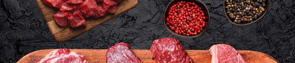 Sélection de morceaux de bœuf cru frais sur une planche en bois.