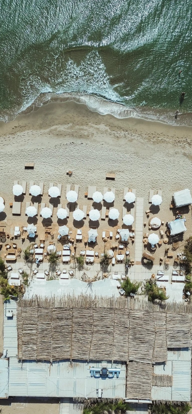 ue aérienne de la plage privée Playa Amor à Leucate, avec lits et transats face à la Méditerranée
