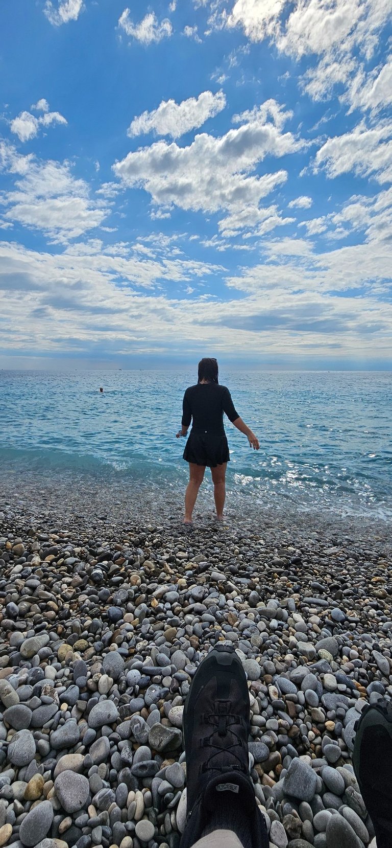 Girl in full coverage bathing suit steps into the Mediterranean in the South of France