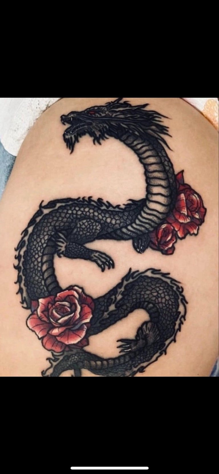 Detailed black ink Japanese dragon tattoo with vibrant red roses on skin.