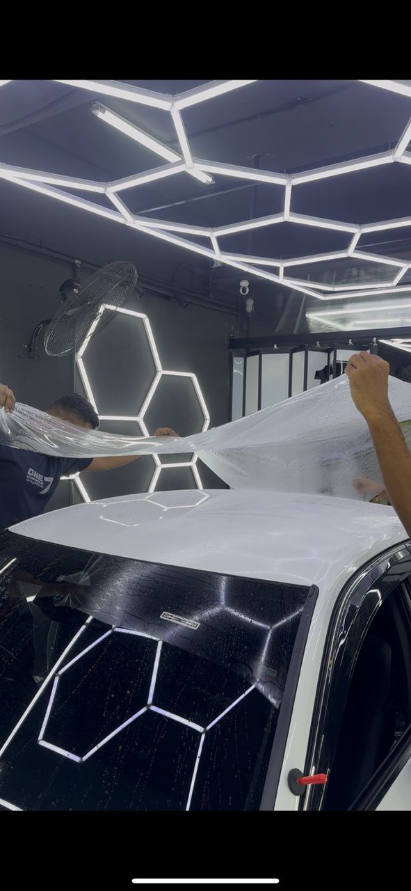 Technicians installing paint protection film on car roof and windshield