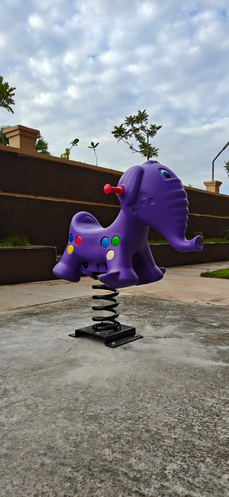 Purple elephant spring rider on a playground with a cloudy sky background.