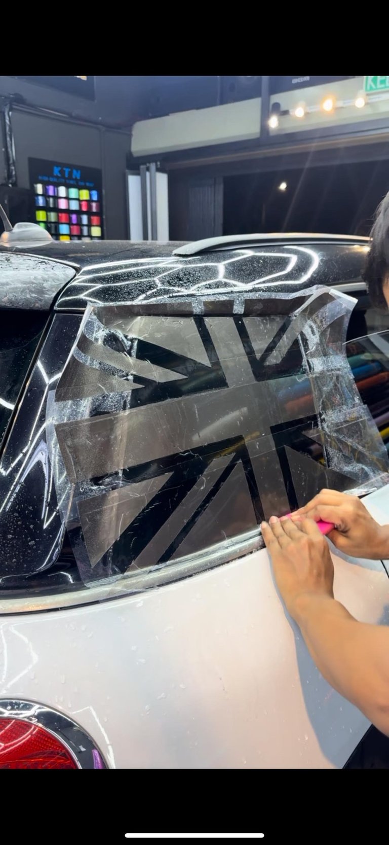 Technician installing Union Jack decal wrap on car rear window