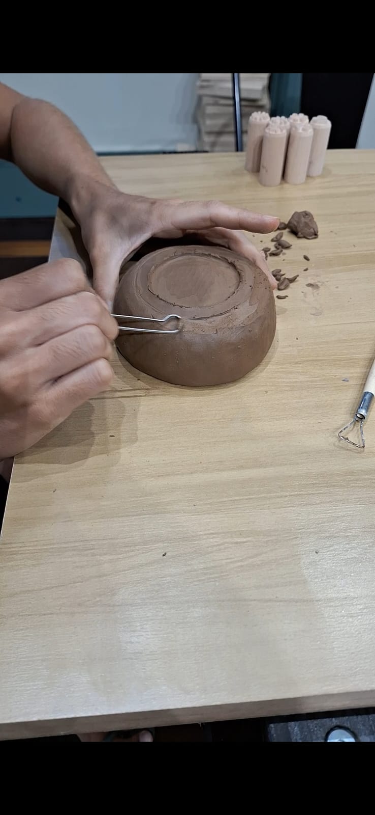 Indica pessoa fazendo acabamento na parte de baixo de uma peça