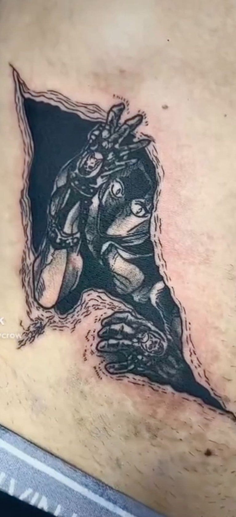 Detailed black and grey anime tattoo of Killer Queen from JoJo's Bizarre Adventure emerging through skin.