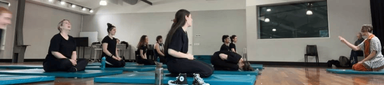 a group of people sitting on blue mats in a gym