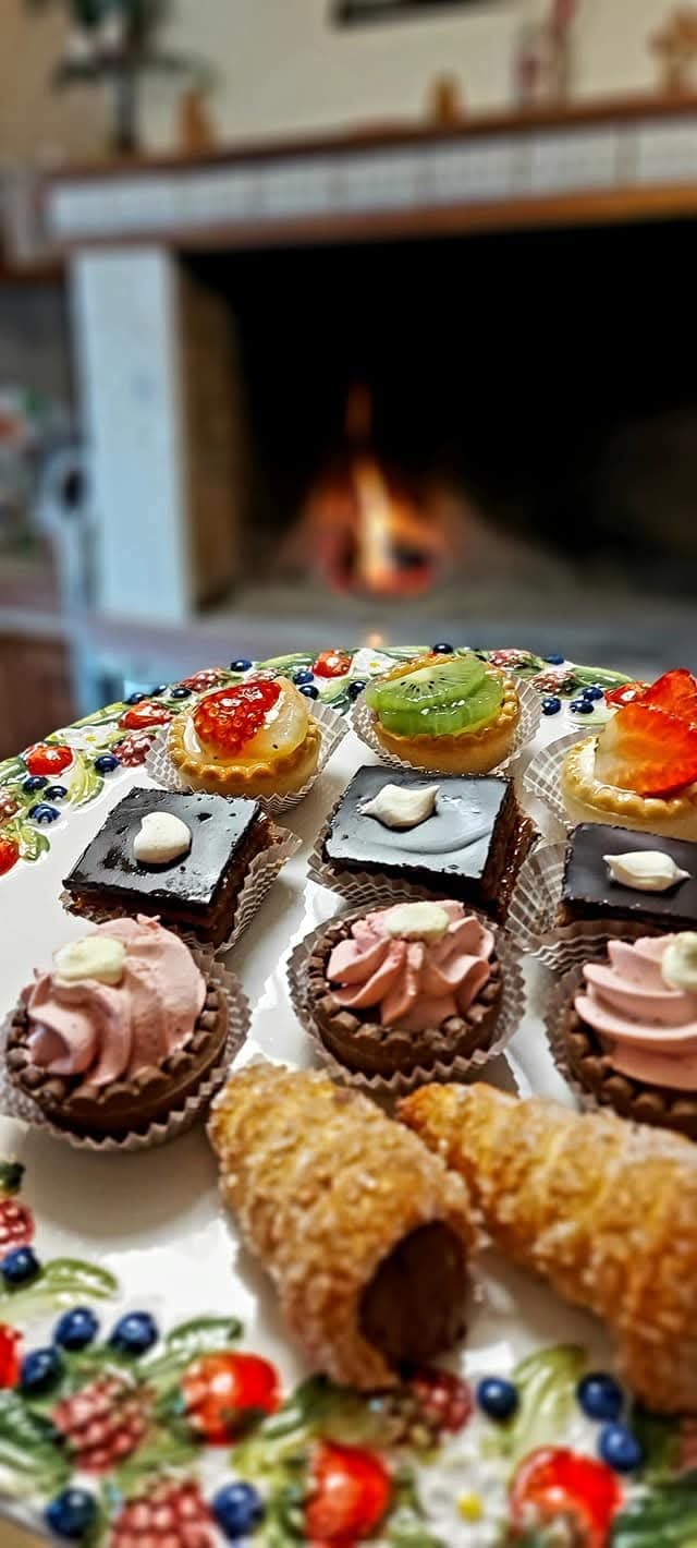 An assortment of gourmet Italian pastries and mini tarts arranged on a decorative plate by a fireplace.