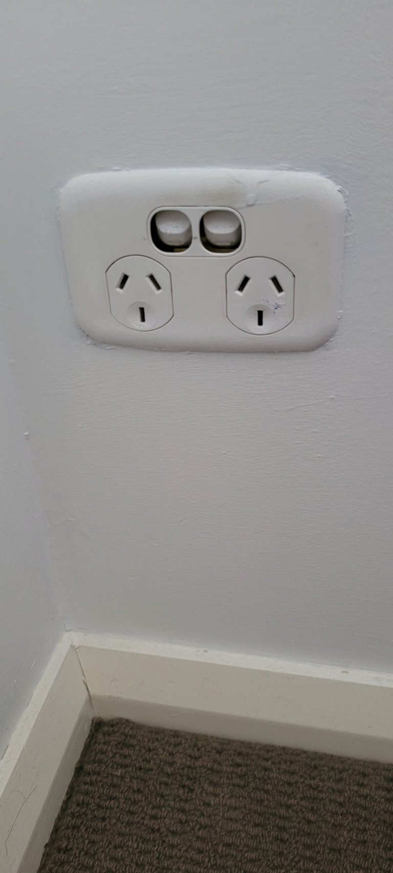 Broken white double power point electrical outlet on a wall