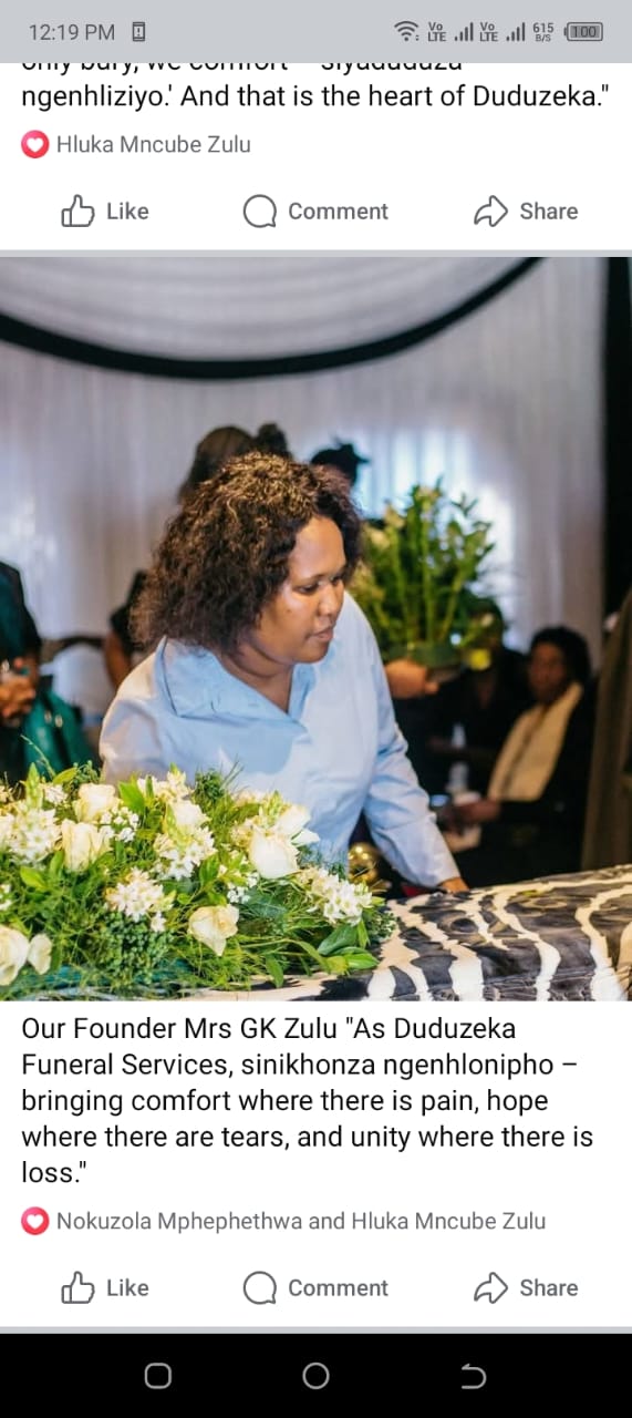 Duduzeka Funeral Services founder Mrs GK Zulu standing by white floral funeral arrangements.