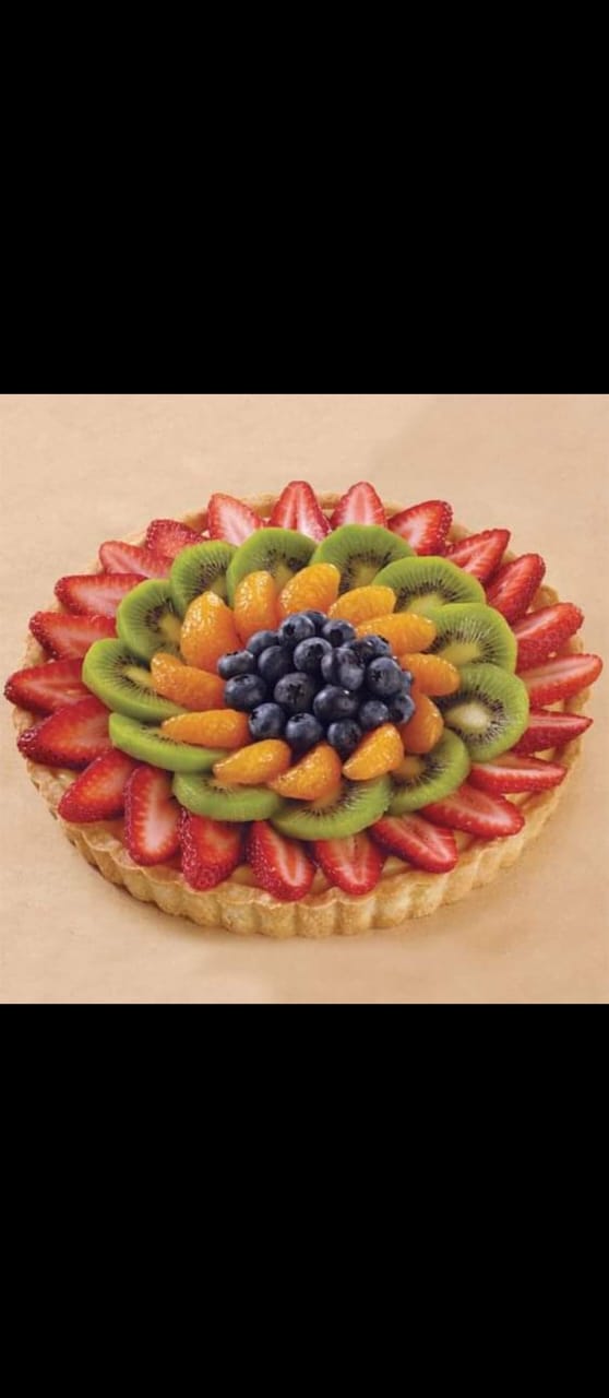 Tarta de frutas frescas cubierta con círculos concéntricos de fresas, kiwi, naranjas y arándanos.