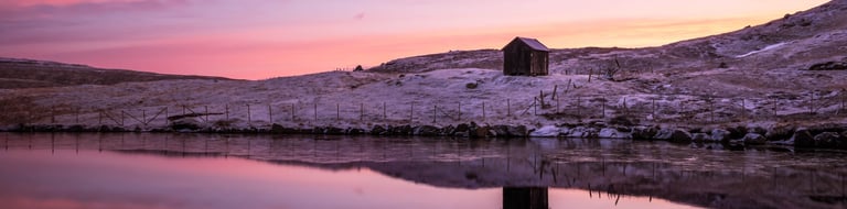 Lake near Nes on Eysturoy reflecting sunset sky and surrounding hills, calm and minimalist Faroe Islands landscape