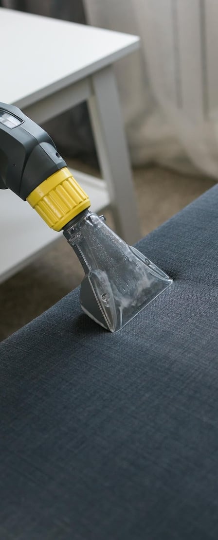 a person using a vacuum cleaner to clean a couch