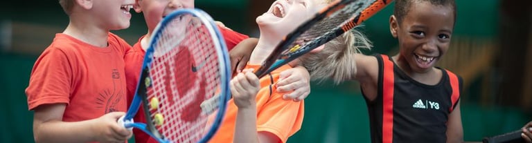 Image avec des enfants qui rigolent et tiennent des raquettes de tennis