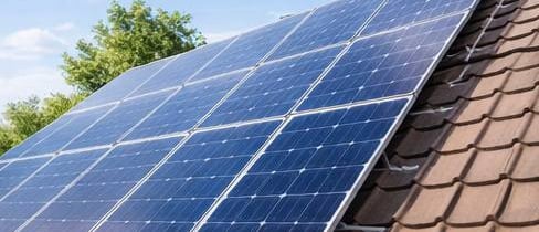 Residential rooftop solar panels installed on a brown tiled roof for renewable energy.