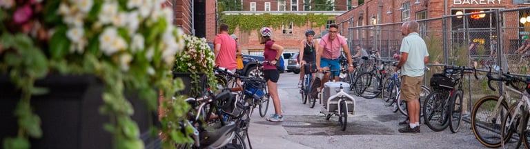 People on and near a large group of bikes downtown in an alley