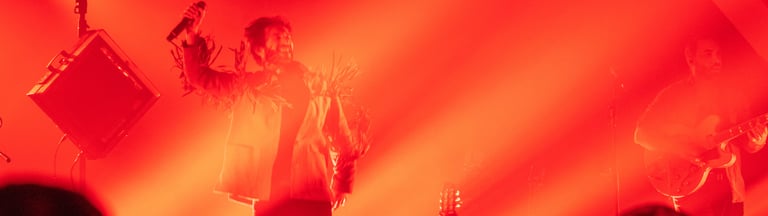 a man in a white shirt and a microphone in front of a red light