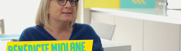 a woman in a blue sweater and glasses sitting at a desk