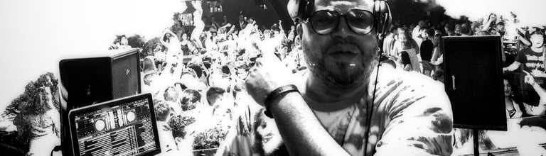 Professional DJ wearing headphones and glasses performing a live set for a crowded dance floor.